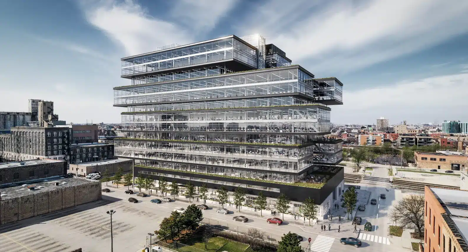 Large glass office building with stacked levels in an urban setting under a blue sky.