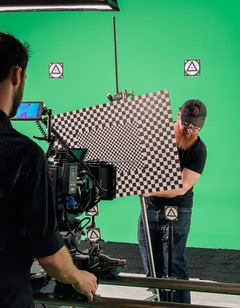 Film production team preparing visual effects shoot with green screen and tracking markers