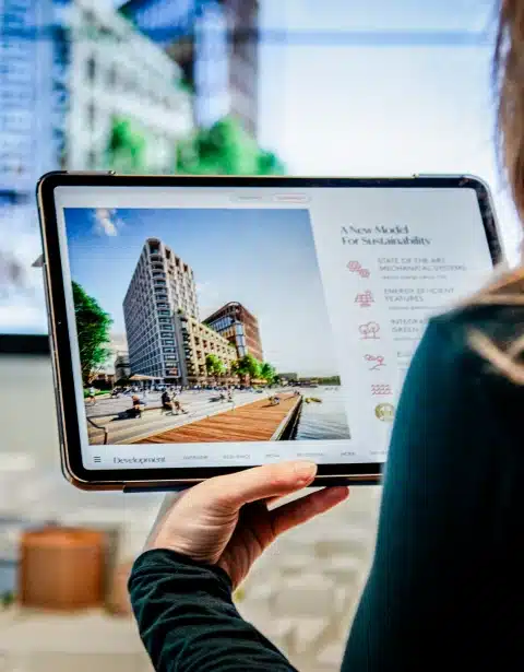 Tablet screen showing sustainable development project interface with building visuals and icons
