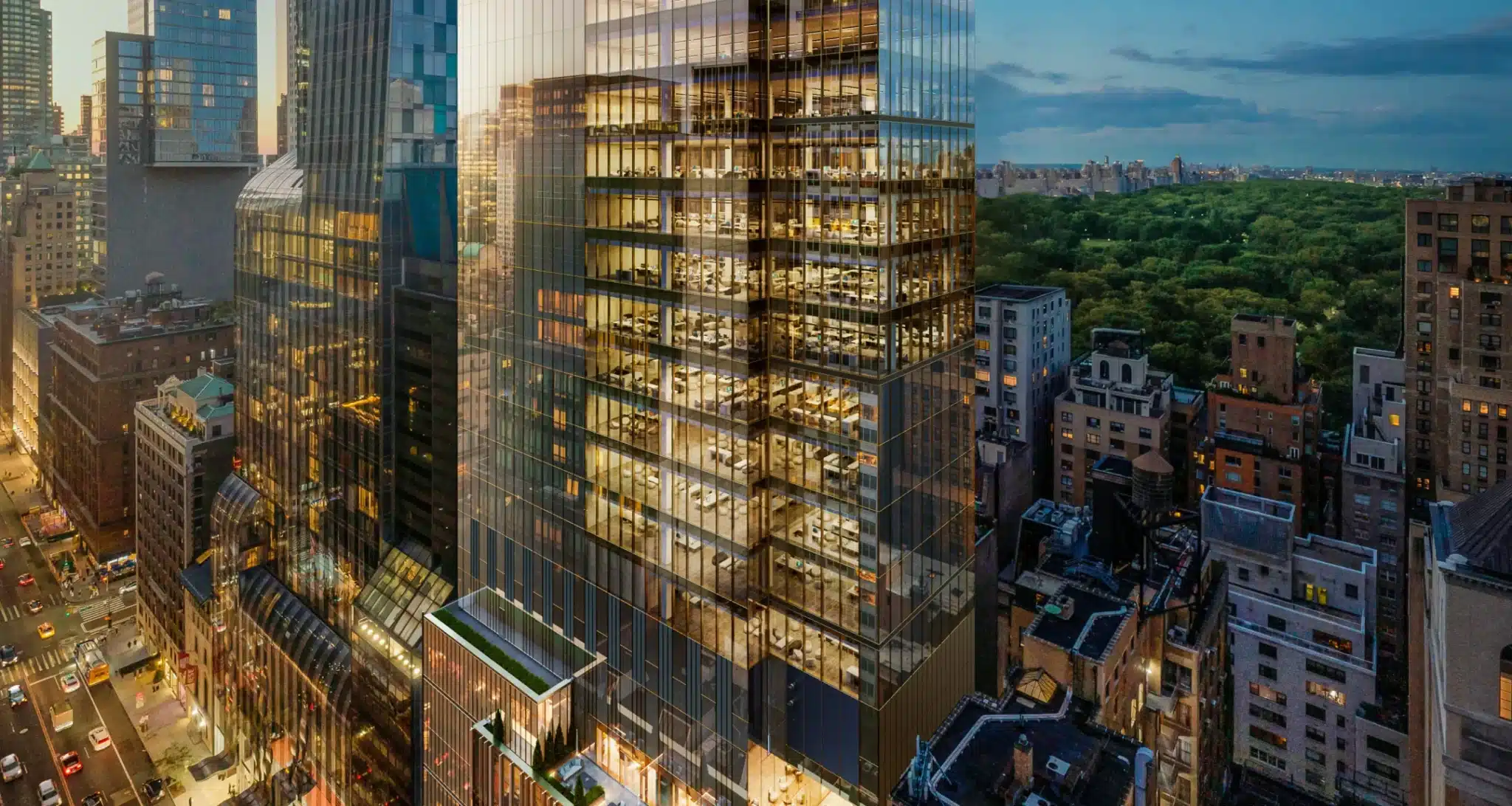 Illuminated skyscraper at dusk with glass facades reflecting city lights near Central Park