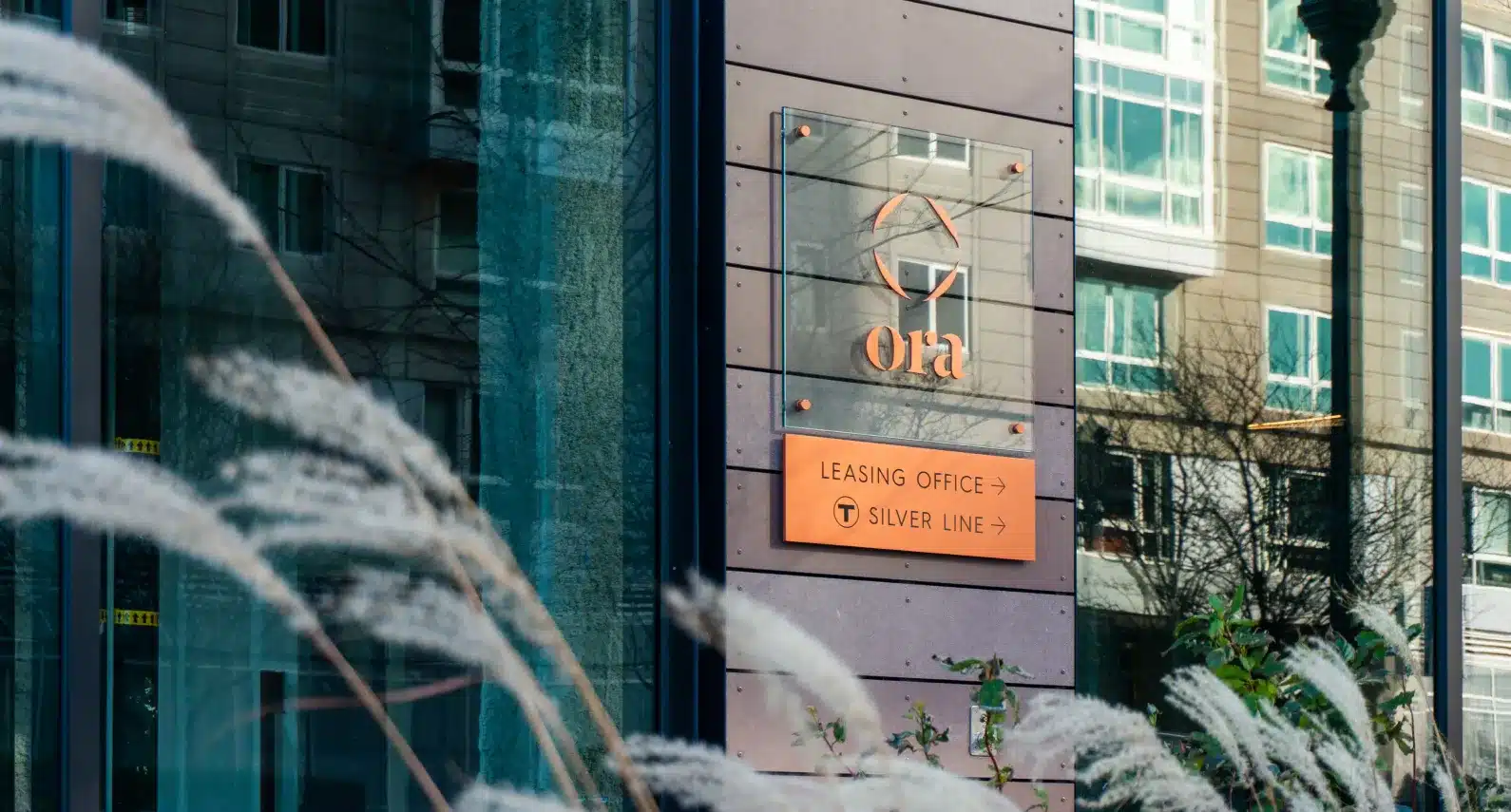 Luxury apartment entrance with Ora branding and directional signage for leasing office