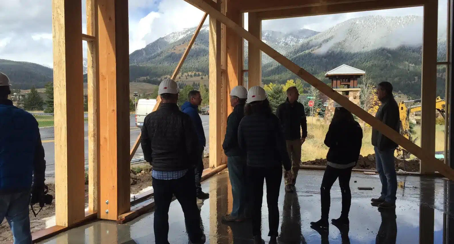 Construction team inside a wooden-framed building under development, overlooking mountain scenery
