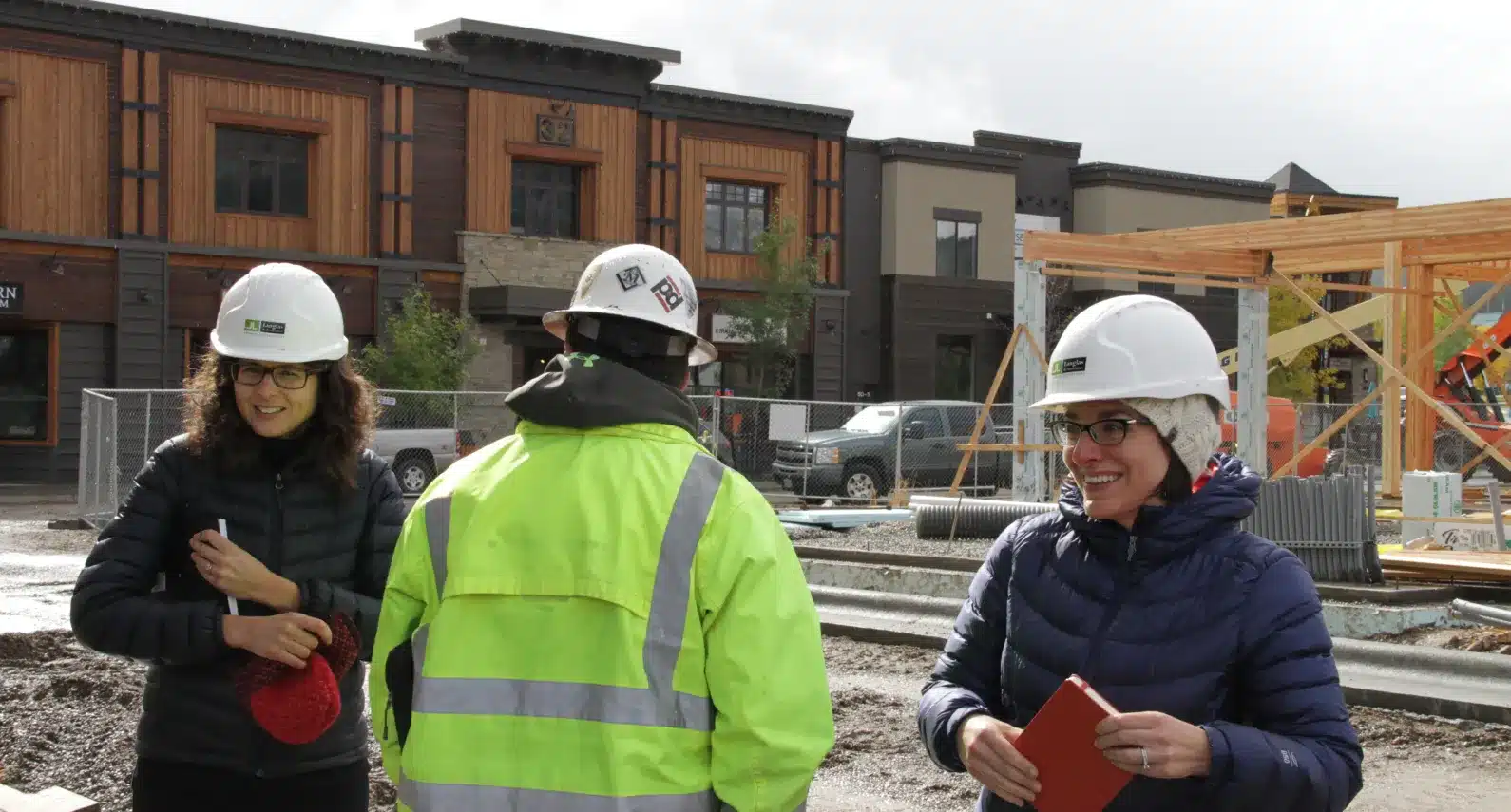 Smiling team members in hard hats talking on-site at a new development project